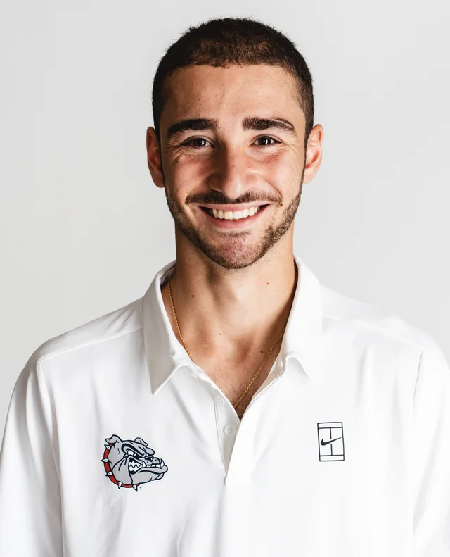 Portrait of Oscar Rashed smiling in a white Gonzaga tennis polo