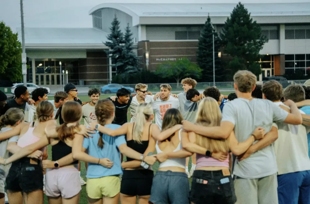 Gonzaga student-athletes in a team huddle on the field at dusk